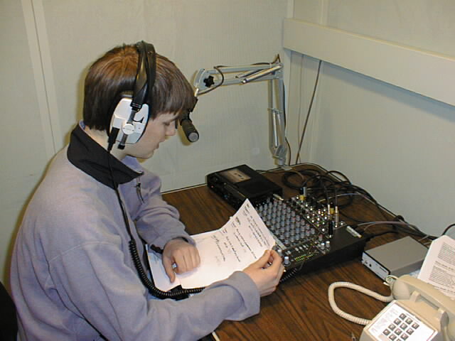 Student reading a weather forecast on live radio in the Bob and Charlotte Landis Broadcast Room